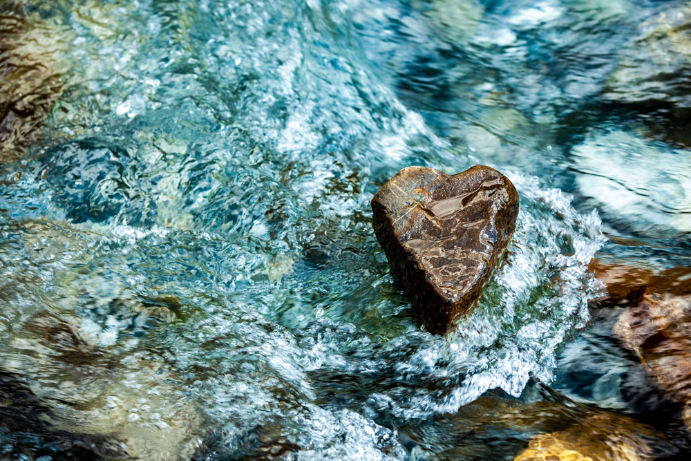 En sten formad som ett hjärta ligger i vatten